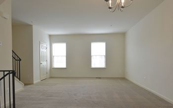 Empty living room with three windows and a chandelier